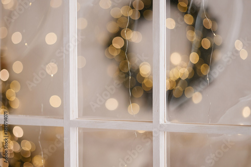 Wallpaper Mural White wooden window frame with glass in an indoor festive setting, showing blurred warm lights and a wreath detail. Suitable for holiday themes, decoration concepts, celebration visuals. Torontodigital.ca