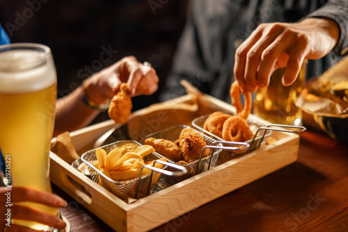 Beer snacks assortment with fries, onion rings and chicken bites
Crispy bar food served in a wooden tray with beer
Fried appetizer platter being shared at a pub