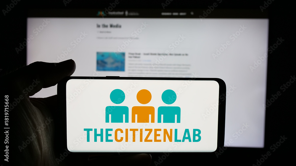 Fototapeta premium Stuttgart, Germany - 11-19-2025: Person holding cellphone with logo of Canadian research laboratory Citizen Lab on screen in front of webpage. Focus on phone display.