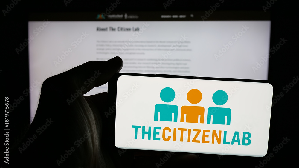 Fototapeta premium Stuttgart, Germany - 11-19-2025: Person holding mobile phone with logo of Canadian research laboratory Citizen Lab on screen in front of web page. Focus on phone display.