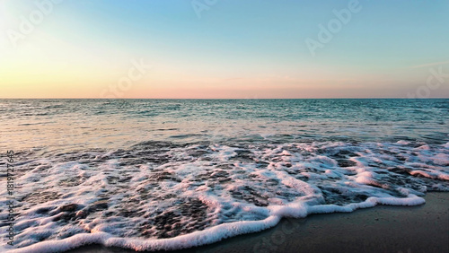 Photos Gentle ocean waves softly approach sandy beach, creating calming seaside scenery during colorful sunset sky