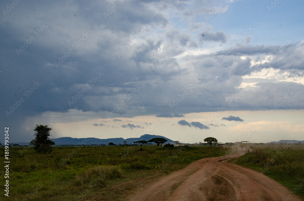 Obraz premium Dramatic clouds over the African savannah with a safari vehicle