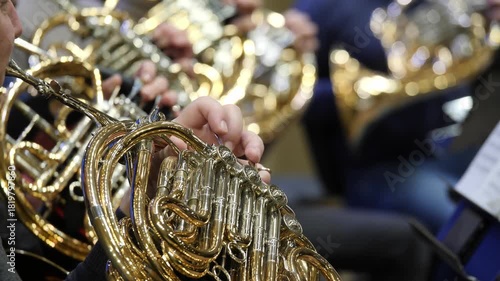 Close-up of musicians playing shiny French horns during rehearsal