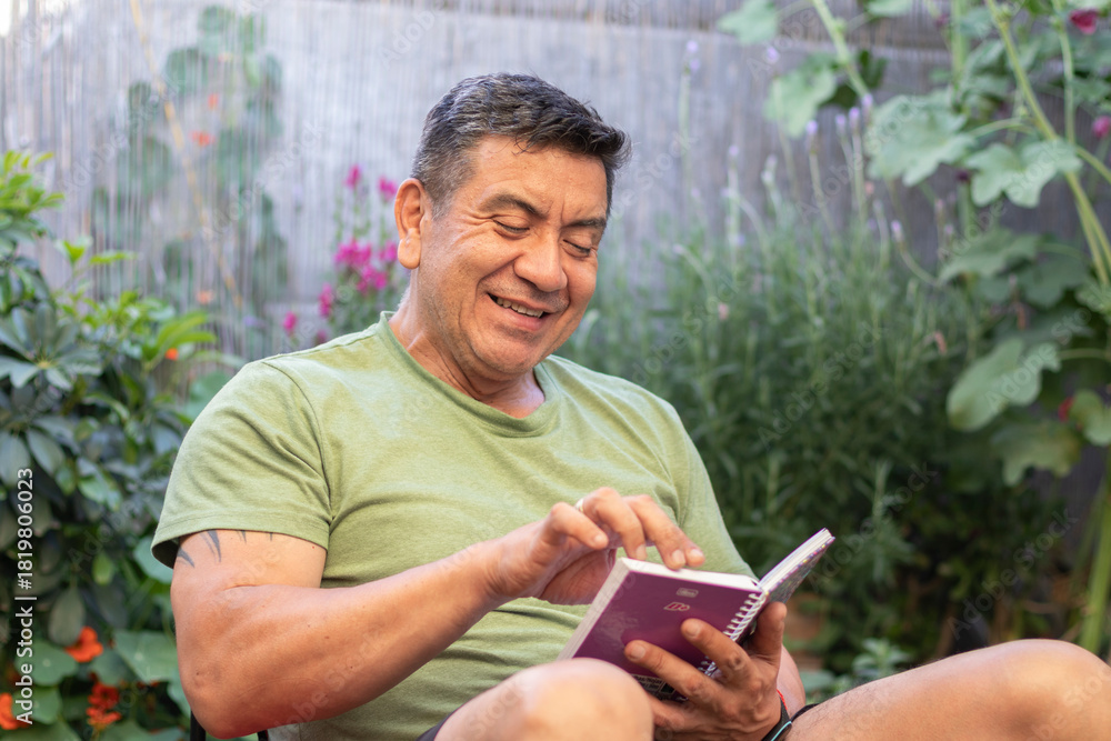 Obraz premium Hombre de 60 años con ropa deportiva leyendo una libreta de apuntes rodeado de un jardín verde