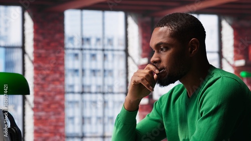 Fotografía Black man doing remote work feeling uneasy and anxious at desk, shaking his legs and being jittery due to task completion and deadline