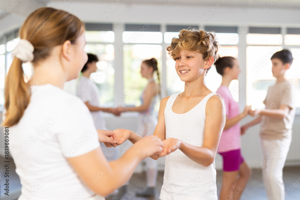 Fototapeta premium Girl dances incendiary tango with male teenager partner during choreography lesson. Group training and rehearsal, preparation for competitions