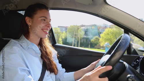 Young happy woman driving her car with a smile. Cheerful female driver enjoying a road trip on a beautiful sunny day