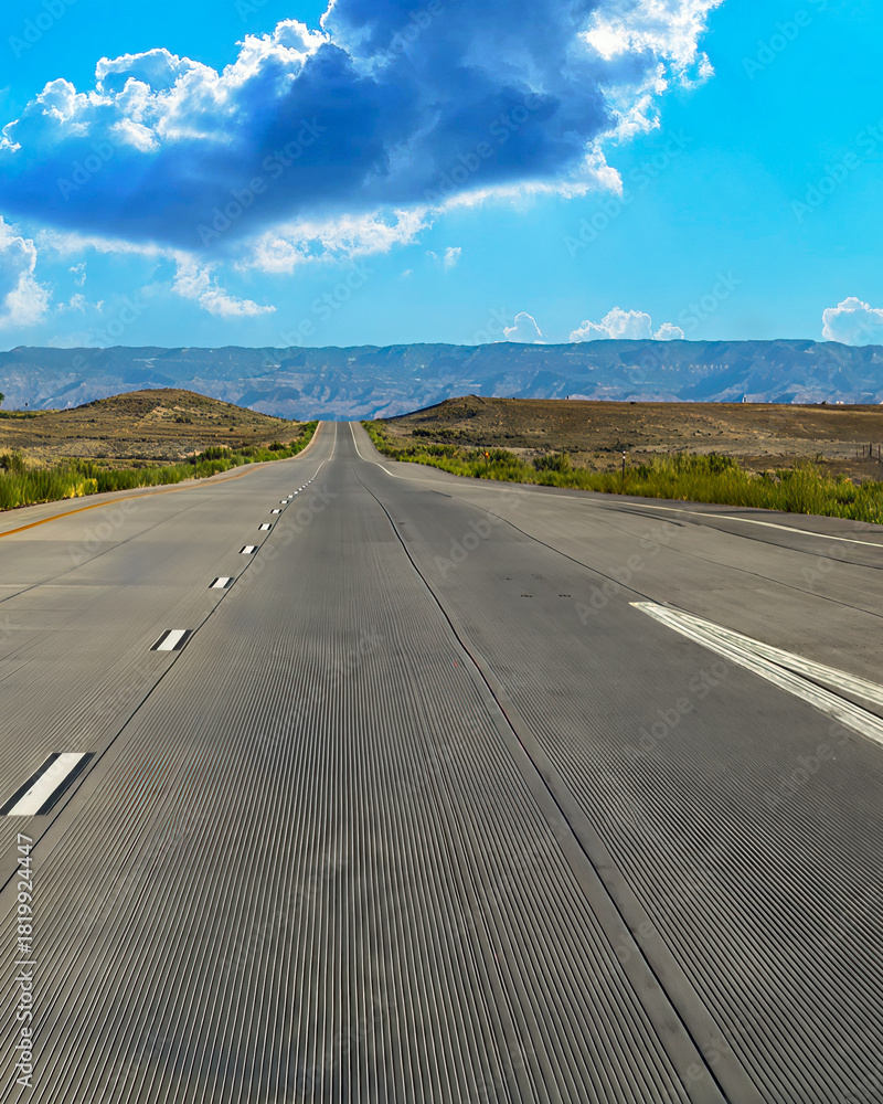 Naklejka premium Open highway through desert hills under bright blue sky 4:5