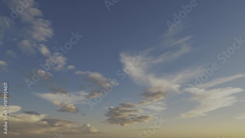 Beautiful blue sky with dynamic, wispy clouds transitioning to a warm golden glow at the horizon, suggesting dawn or dusk.
