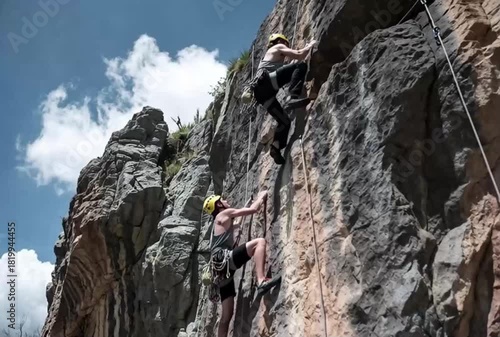 Dynamic rock climbers ascend a steep cliff face under a bright, expansive sky, showcasing strength, adventure, and the thrill of outdoor challenges