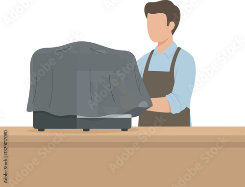 A person in an apron unveils a machine covered with a gray cloth.