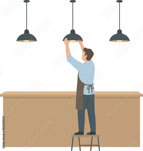 Man in apron standing on stool, reaching up to adjust a hanging light fixture above a counter.