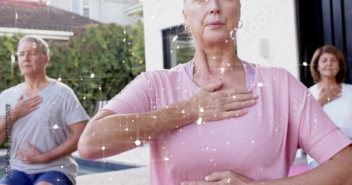 Mature woman kneeling on mat holding chest and belly camera pushing in sparkles overlaying wellness