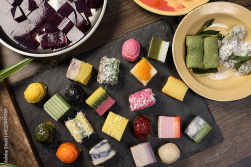 Traditional Malaysian desert Nonyah Kuih making preparing ingredients panadn leaf shredded coconut gula melaka  agar agar sagu spread over black slate messy rustic wood