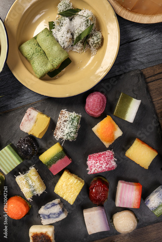 Traditional Malaysian desert Nonyah Kuih making preparing ingredients panadn leaf shredded coconut gula melaka  agar agar sagu spread over black slate messy rustic wood