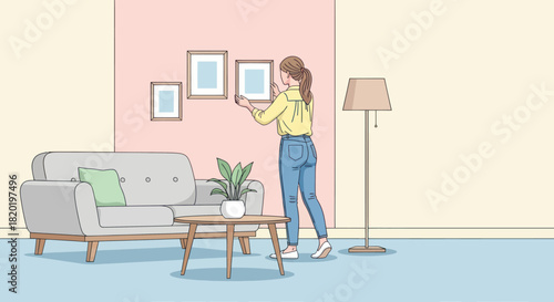 Woman decorating living room by hanging picture frames