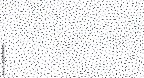 A close up of a white surface with tiny black confetti scattered in a randomized pattern.