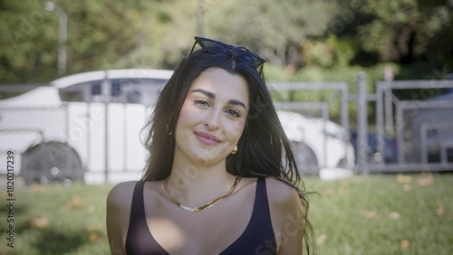 Smiling woman in casual outdoor setting with greenery