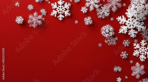 White paper snowflakes scattered on a red background, with a red and white Christmas tree in the background.