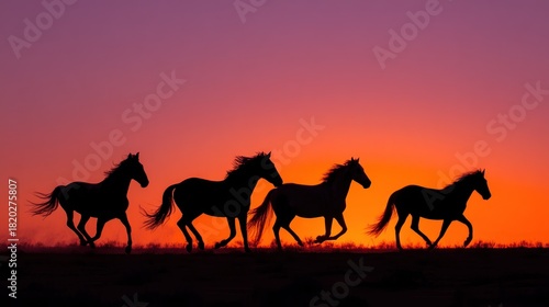 Four wild horses galloping across a vibrant sunset sky, silhouetted against a colorful backdrop.