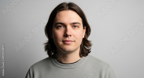 portrait of a young man with shoulder-length dark hair and calm