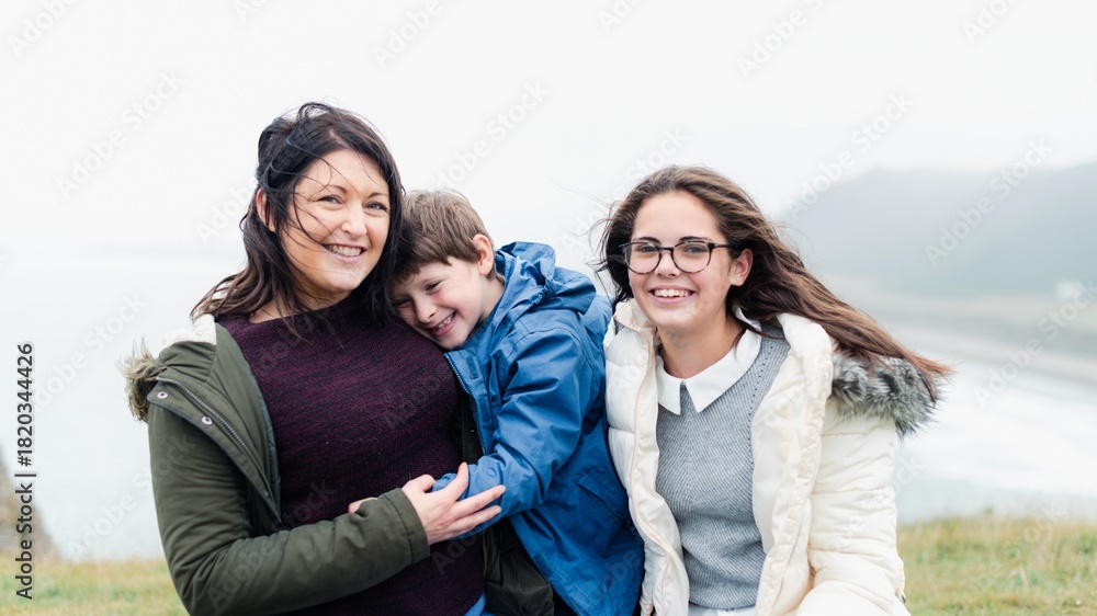 Obraz premium Happy family enjoy windy day outdoors, nature family travel. Mother with children smile together in nature, outdoor family travel. Happy family travel in windy outdoors nature, smile and enjoy