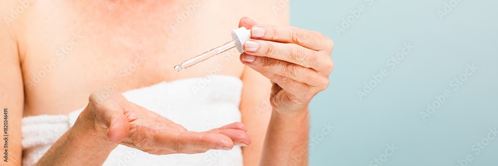 Naklejka premium Woman applying serum with a dropper. Skincare routine with serum. Close-up of hands and dropper. Woman using serum for skincare. Skincare and serum application.