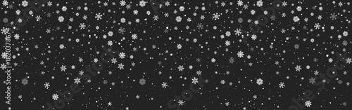 Falling white snowflakes scattered on a dark black winter night background for seasonal and holiday designs