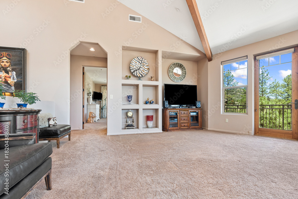 Fototapeta premium A spacious living room featuring a vaulted ceiling and a flat screen tv