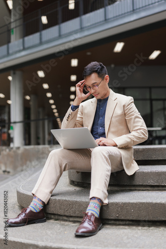 Asian businessman feeling stressed working on laptop outside