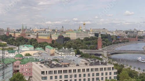 Red walls and golden domes overlook Moscow River under cloudy sky.