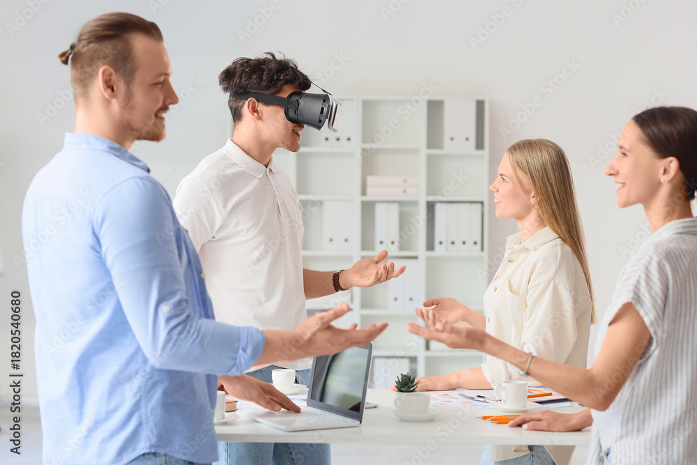 Fototapeta premium Young man using VR glasses with his colleagues in office