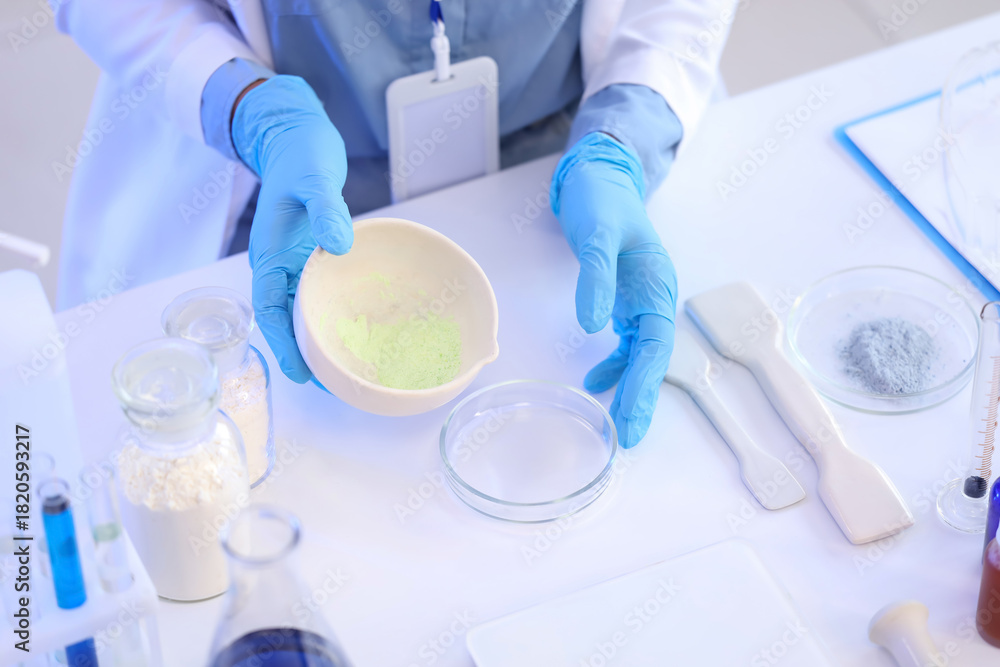 Fototapeta premium Young female chemist with mortar and Petri dish working in lab, closeup