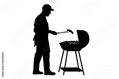 Silhouette of person wearing apron and cap grilling sausages on charcoal barbecue grill