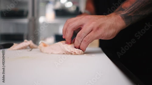 Close-up of a professional chef cutting chicken meat on a restaurant cutting board