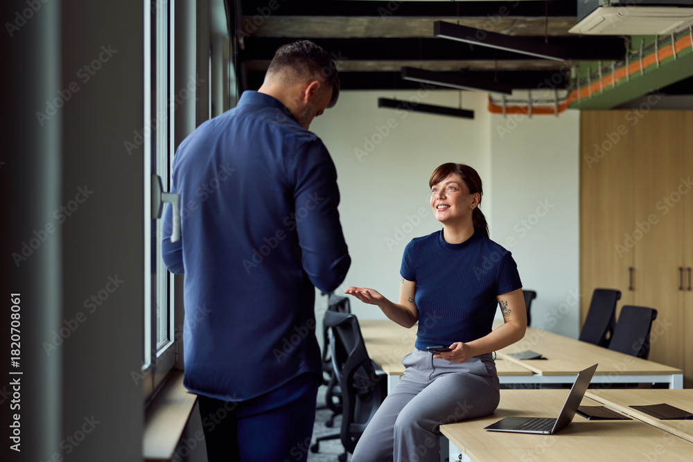 Obraz premium Professional Conversation Between Colleagues In A Modern Office With Laptop And Phone During A Casual Meeting Setup