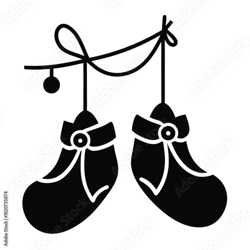 Pair of black baby shoes hangs from a rope, with a small ball