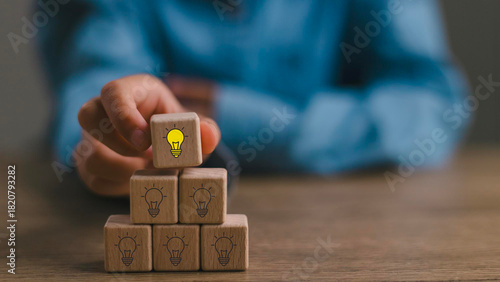 Creative idea, solution and innovation concept. Idea generation and screening for product development process. Wooden blocks with light bulb and yellow color icons on clean background and copy space
