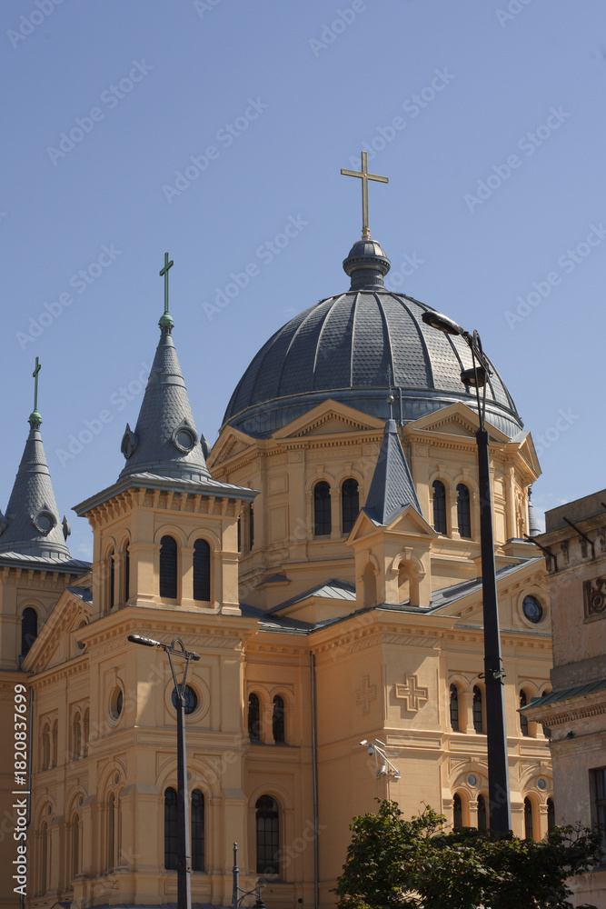 Obraz premium Close-up of a stunning historic Orthodox church, featuring a prominent blue-grey dome, golden cross, and decorative turrets against a clear blue sky