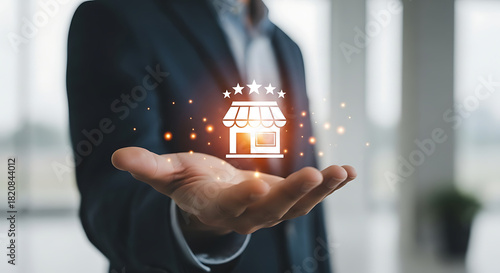 A businessman presenting a storefront icon with stars in his hand with a dark suit and light background