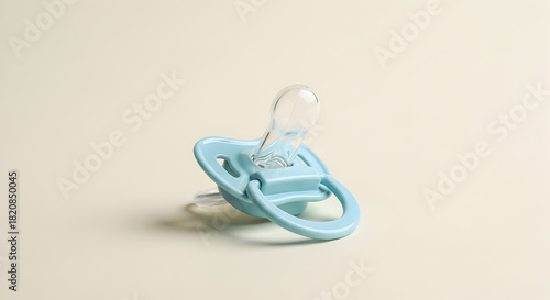 A light blue baby pacifier with a clear silicone nipple resting on a plain, off-white background.