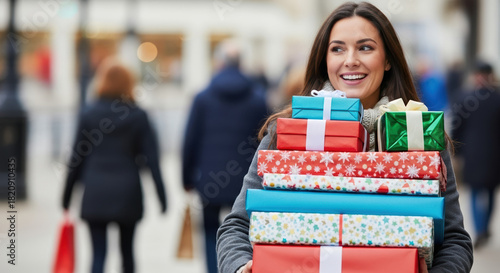 Festive Boxing Day shopping with cheerful woman carrying stack of presents. Enjoy Boxing Day sales and post Christmas shopping with beautifully wrapped gifts and excited smile.