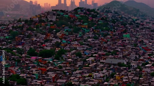Sunset skyline view of San Pedro Garza Garcia skyscrapers rising above colorful hillside residential neighborhoods in Monterrey.