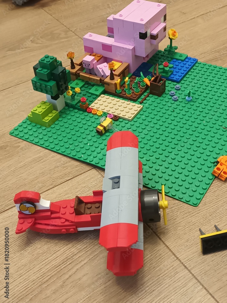 Naklejka premium Red Biplane Lego and Minecraft Pig House on a Green Baseplate