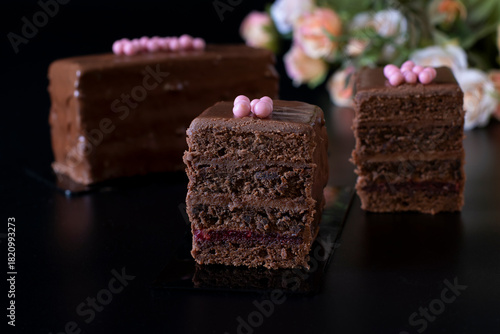 Sliced mousse chocolate desserts with chocolate cream and raspberry marmalade covered gourmet chocolate glaze