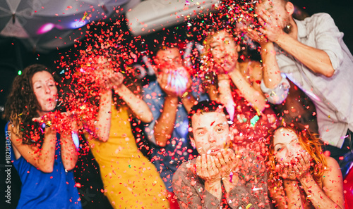 Young friends having party throwing confetti - Young people celebrating on weekend night - Entertainment, fun, new year's eve, nightlife, holidays, concept - Soft focus on bottom man's hands