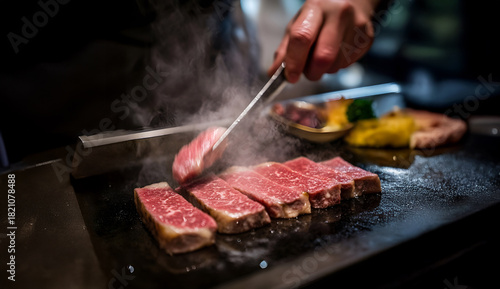 Chef cooking premium beef steak on hot teppanyaki grill