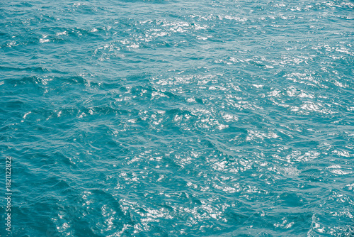 Sea wave texture close up. Dark blue water surface with ripples background. macro blue wave pattern in a river with motion blur. Sparkling sunlight reflecting on the surface of a calm.