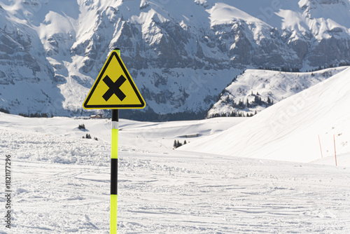 Ski resort danger warning cross sign on snowy mountain slope