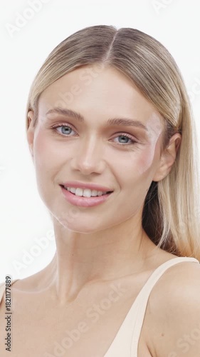 A cute young woman enjoying her clean skin on an isolated background in a vertical video. Concept self care and natural beauty